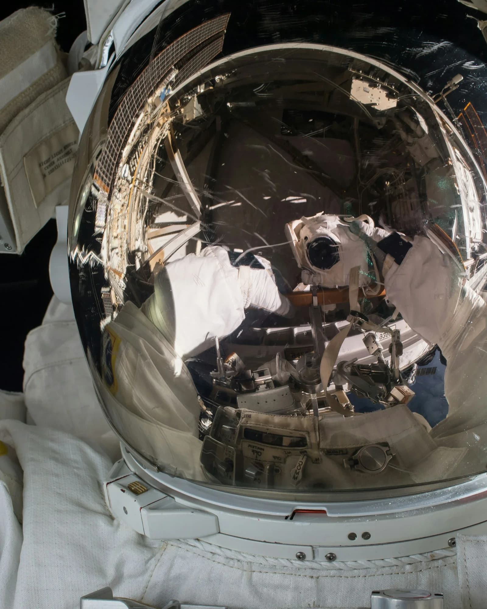 Astronauten-Helm aus nächster Nähe, im Visier spiegelt sich die Raumstation