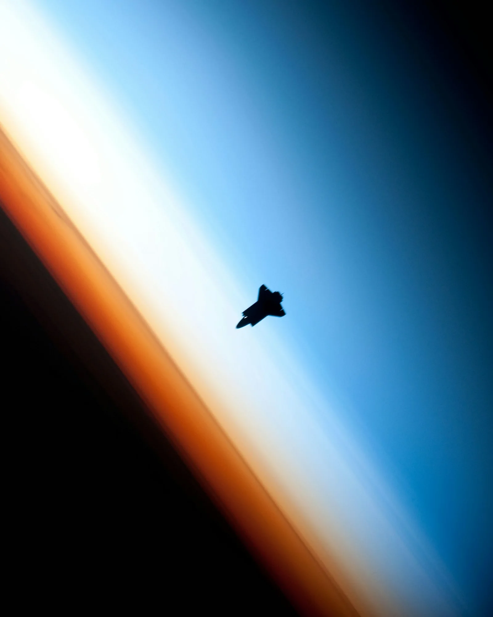 Space-Shuttle als Silhouette vor dem orbitalen Sonnenaufgang über der Erdatmosphäre